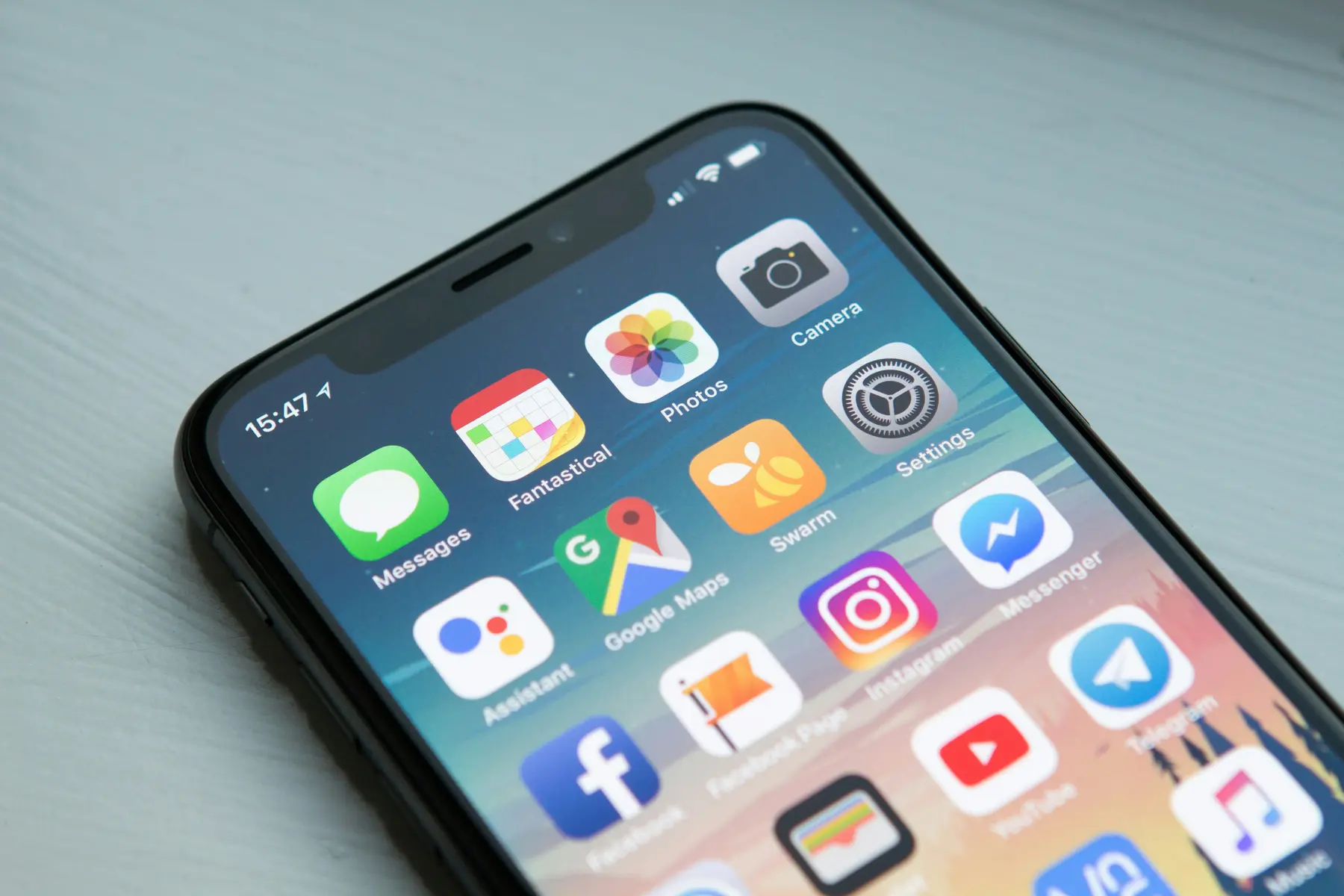 A smartphone lying on a wooden surface showing a grid of app icons including Messages, Maps and Instagram.